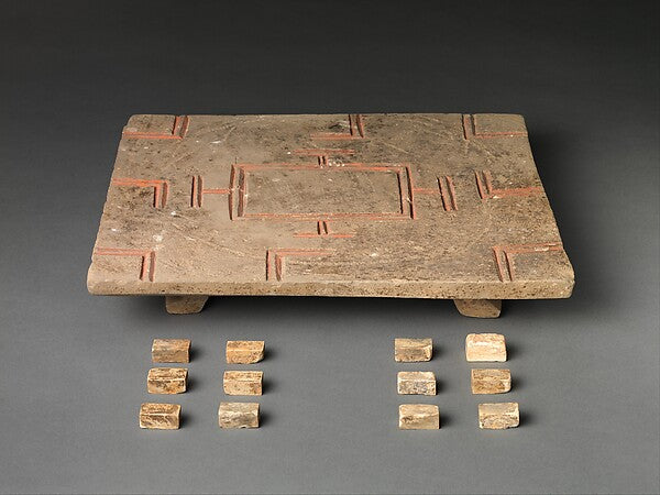 A Han-dynasty Chinese earthenware Liubo board and playing pieces showing the game's distinctive TLV-shaped markings, from The Metropolitan Museum of Art.