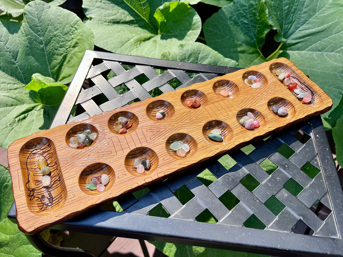 Handcrafted wooden Mancala board with two rows of cups and smooth playing seeds